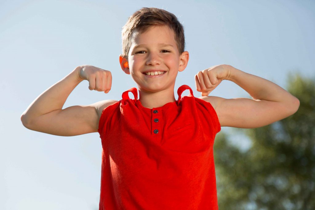 boy in red shirt showing his strength