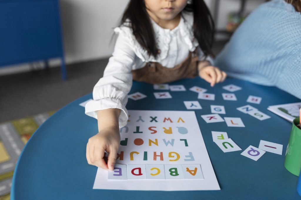 Girl doing activity matching letter cards on alphabet sheet