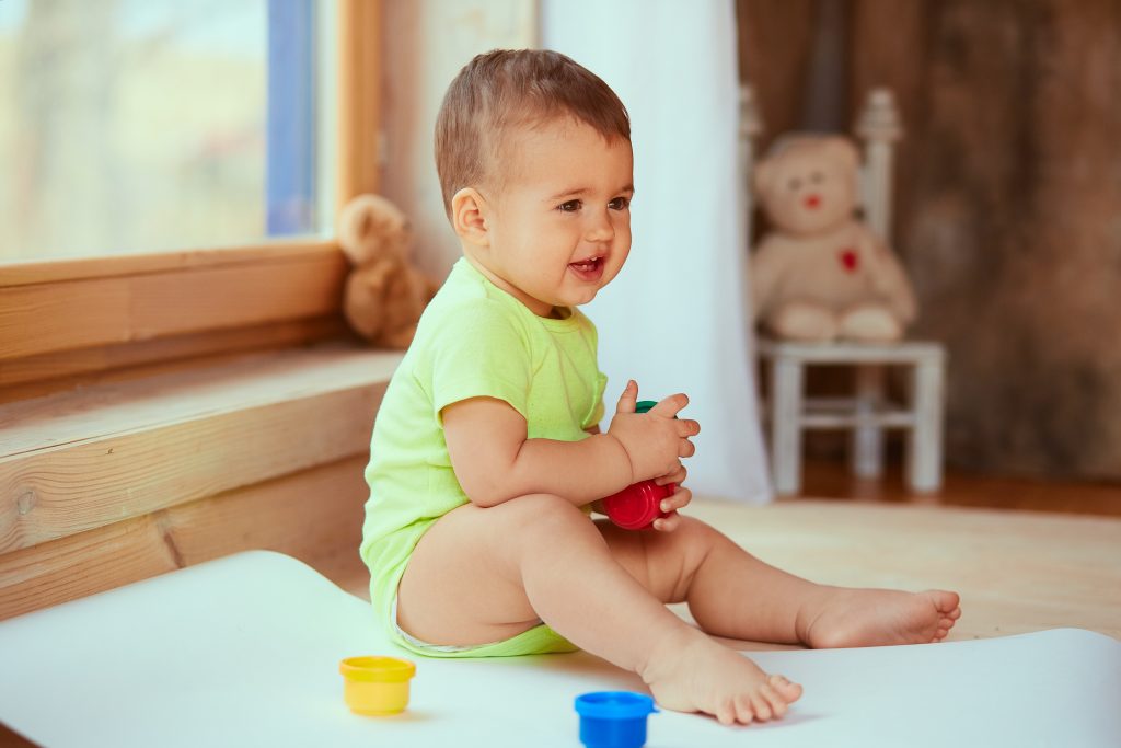 baby holding box of paints