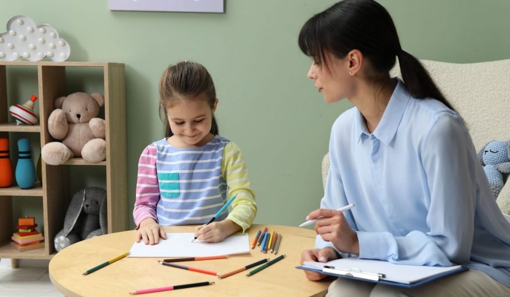 Child and therapist sit at table, working