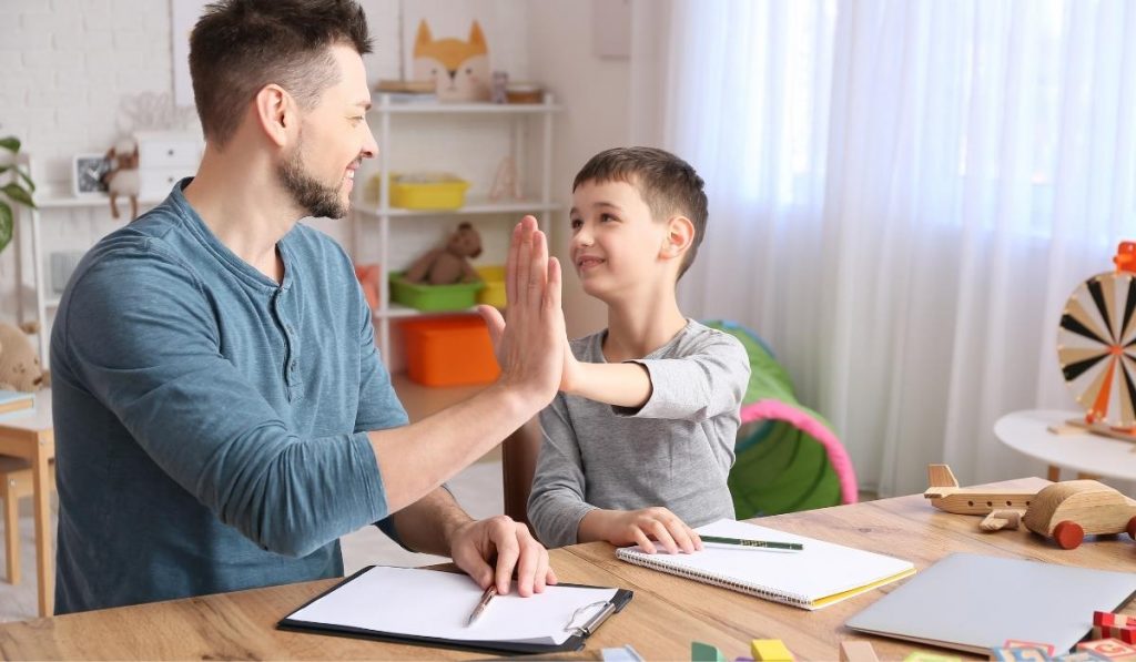 Child and therapist high-five each other