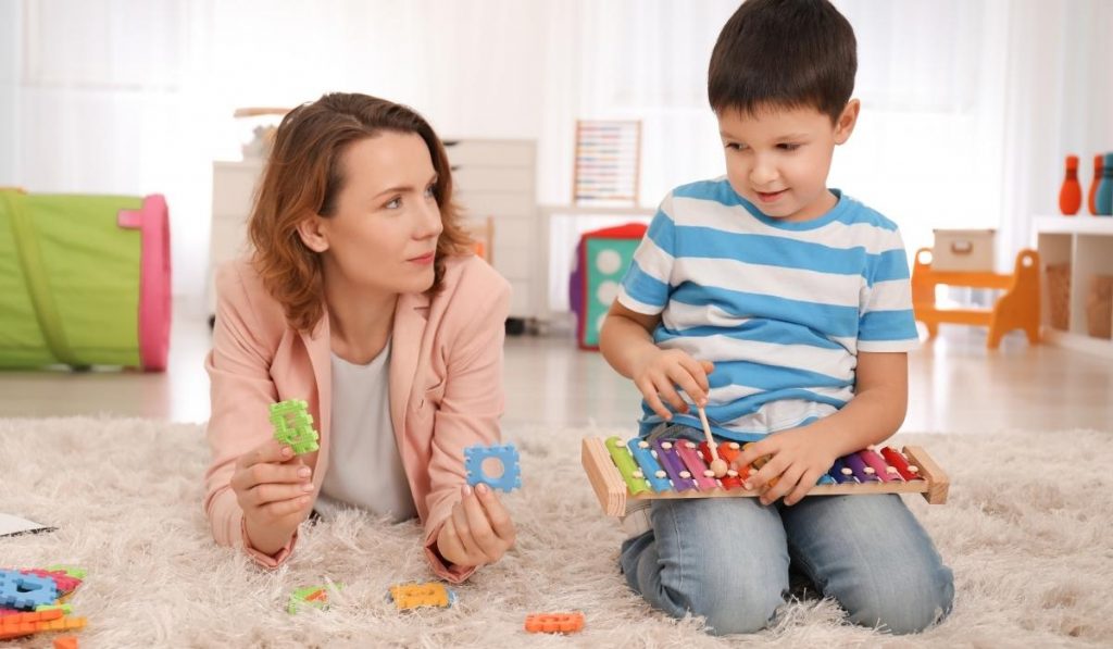 Therapist playing with child on floor with xylophone