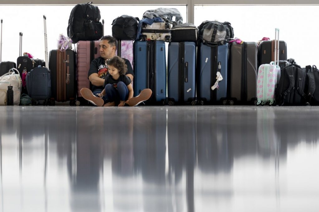 Father and child sit on the floor at an airport