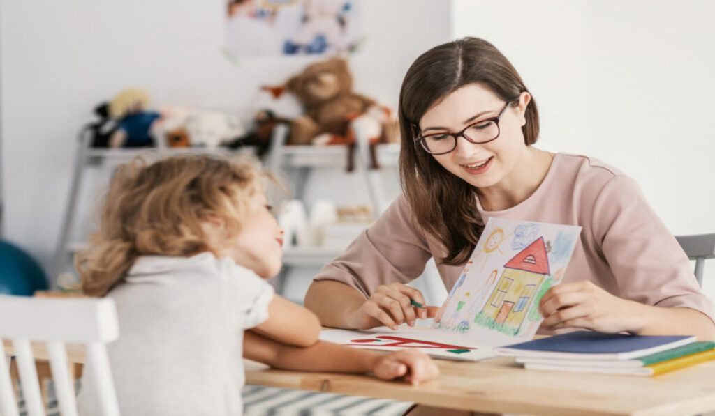 Child discussing picture of house with therapist