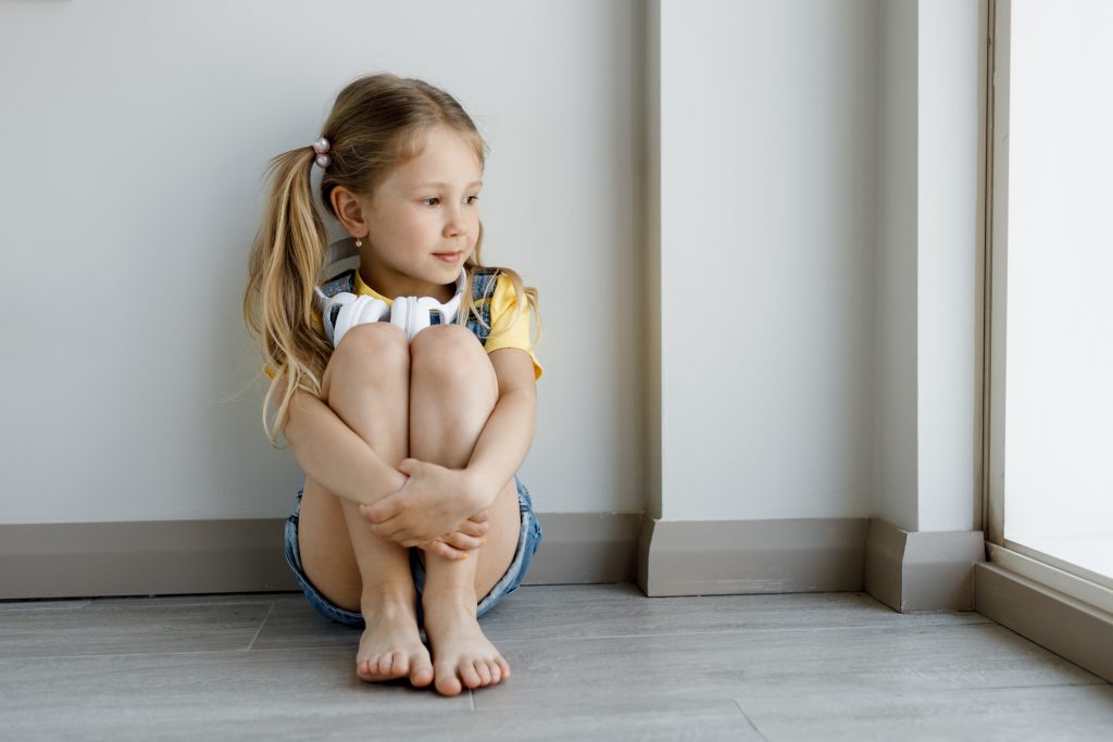 Young girl with headphones looking out the window
