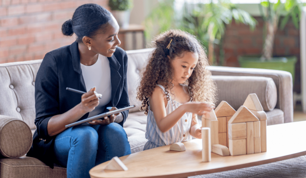 Girl building block house in therapy