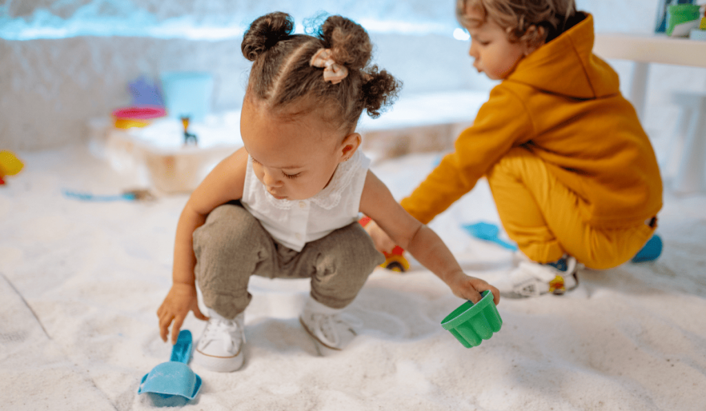 Toddler girls playing in sand box