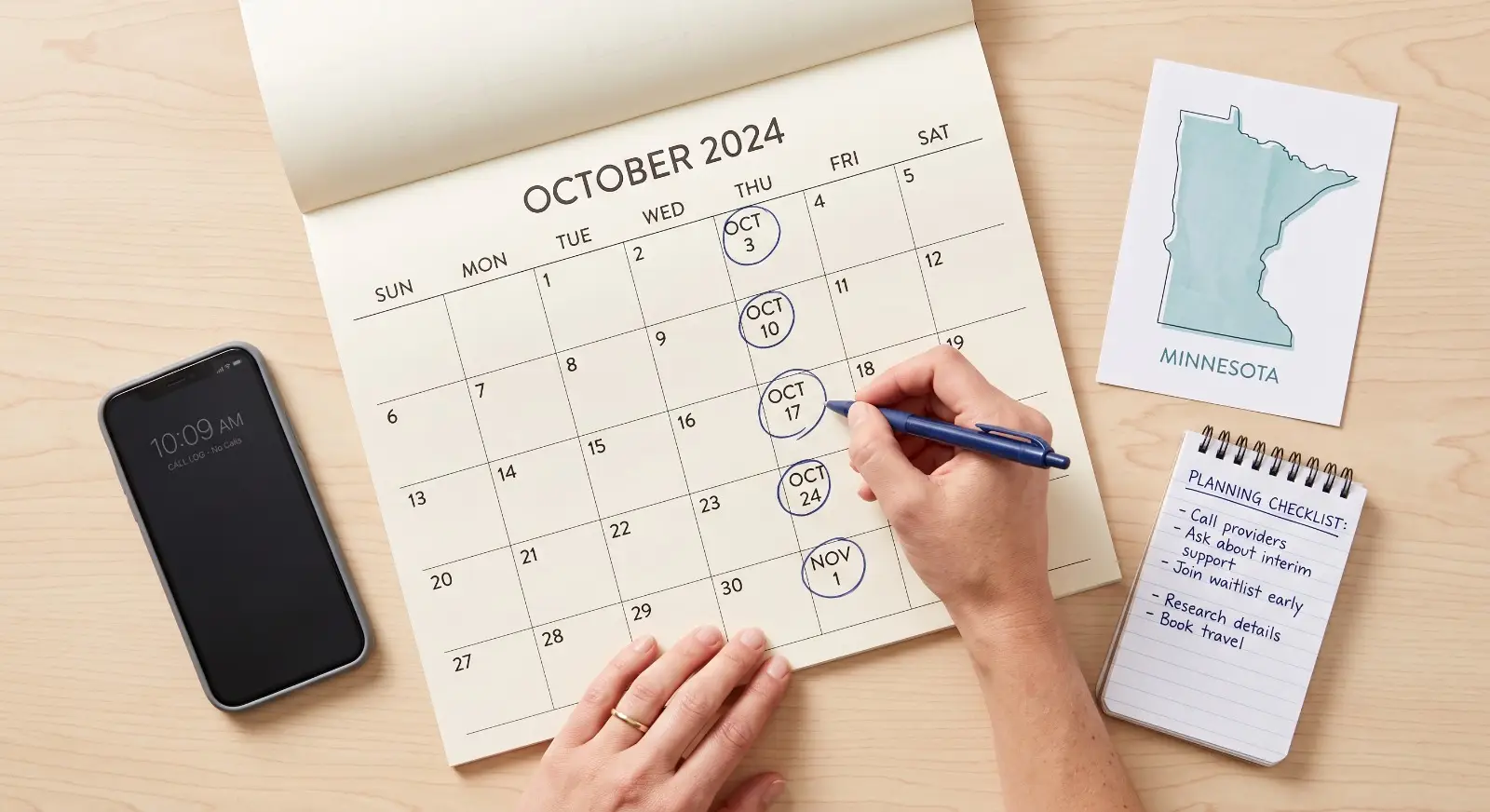 A hand circles a future date on a paper calendar next to a printed outline map of Minnesota, a notepad with a short planning checklist, and a phone with a blank call log, in a clean flat-lay composition.