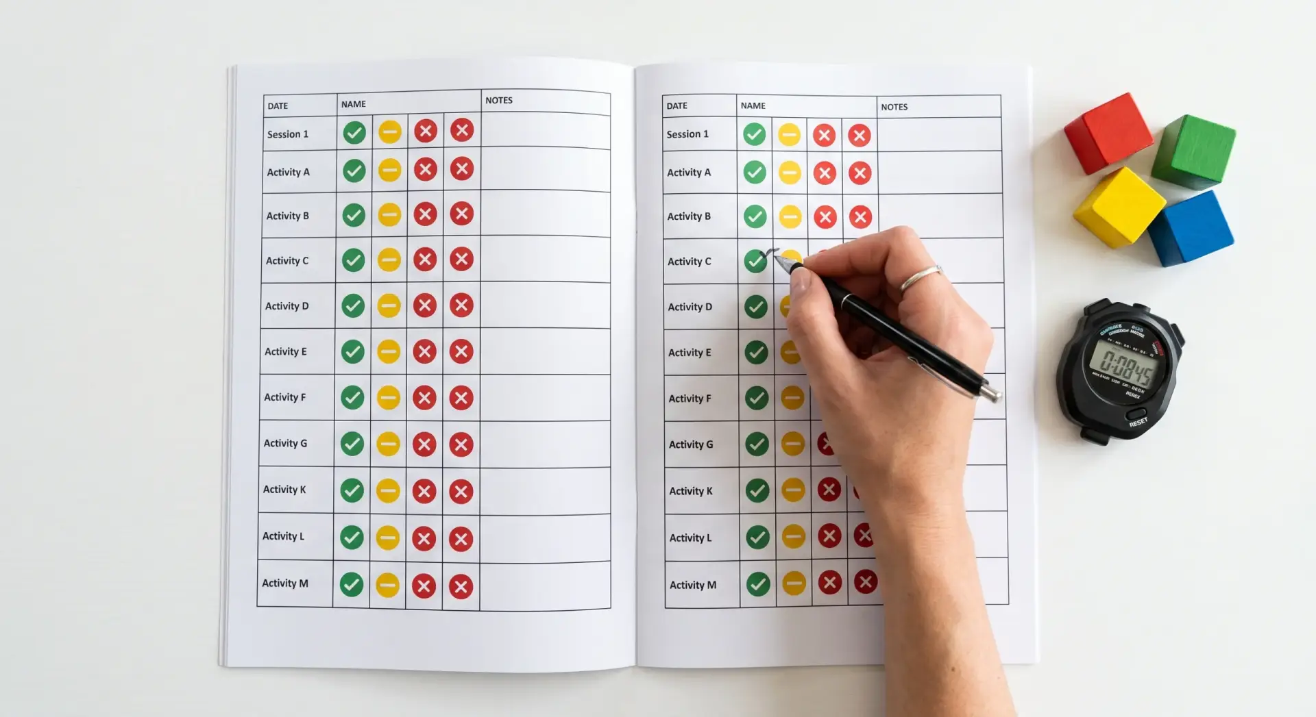 A clean, straight-down flat-lay photograph of an open assessment booklet with rows of small rating icons in green, yellow and red, a compact timer/stopwatch and a few colored sorting blocks beside it, a hand marking one icon with a pen. Even, bright, high-key lighting, minimal shadow. Neutral white-paper background with the semantic green/yellow/red icons as the only saturated color. Methodical, careful, informational mood. No readable brand text or logos.
